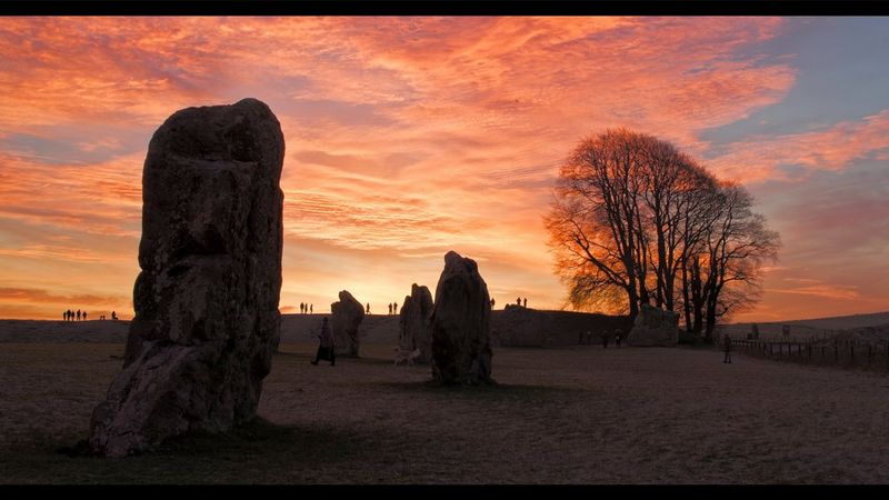 一部电影仍然显示田野里的四块大石头，太阳在它们身后升起，分级后色彩鲜艳。