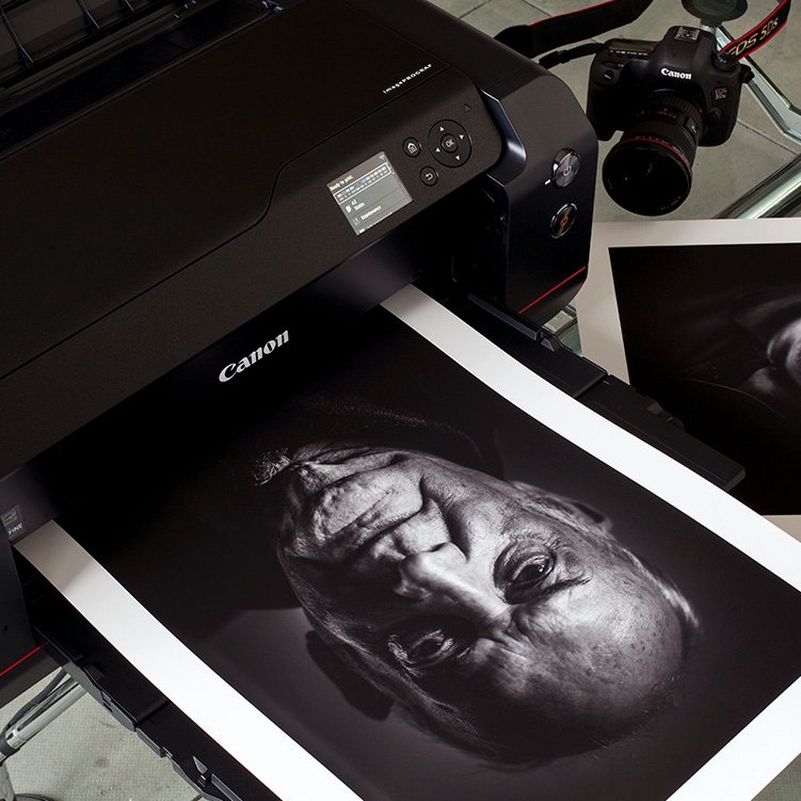 Принтер Canon печатает черно-белый портрет пожилого человека.