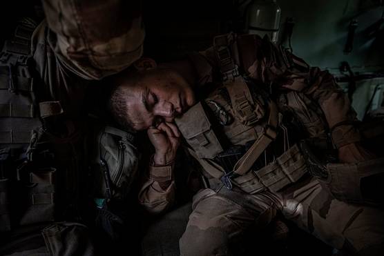 A French Foreign Legion soldier, in full uniform, sleeps sitting up inside an armoured vehicle.