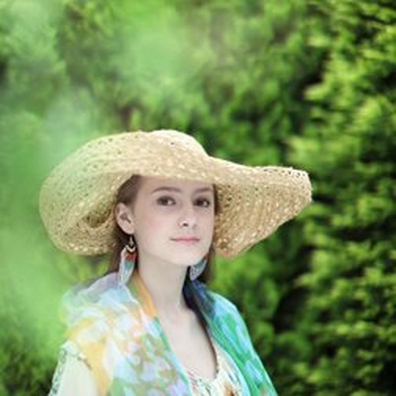 A photo of a woman wearing a straw hat in a garden.