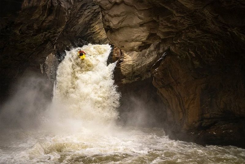A kayaker speeds down a gushing canyon in low light. Shot on Canon.