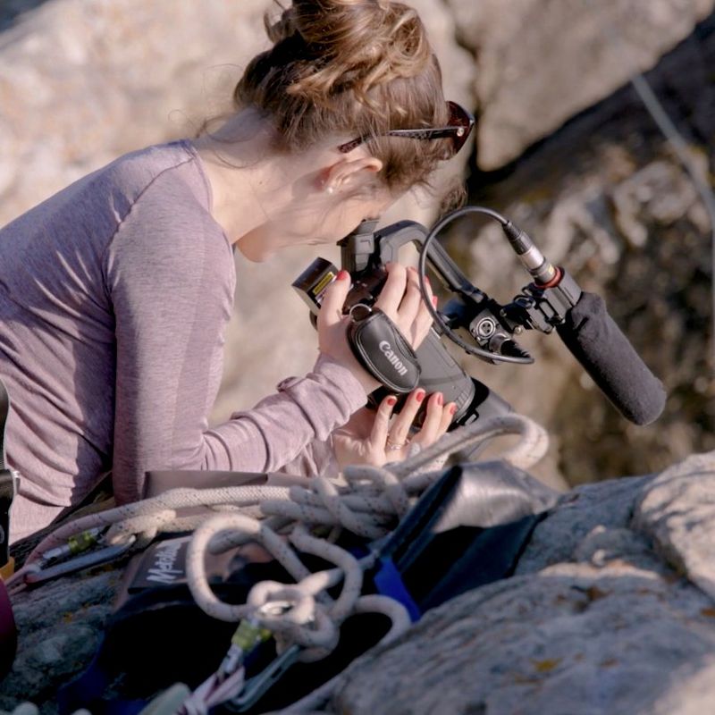 A video still showing journalist and cinematographer Elisa Iannacone filming with the Canon XA55 camcorder while cliff camping in Wales.