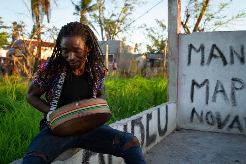 Un homme avec des dreadlocks jouant du tambour dans un studio d'enregistrement détruit à Beira, au Mozambique.