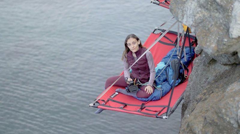 La journaliste Elisa Iannacone, assise sur une tente de paroi, suspendue à une falaise au Pays de Galles.