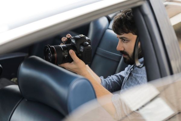 Cinematographer Christian Anderl in the rear seat of a motor car, filming with a Canon ֽ_격-.