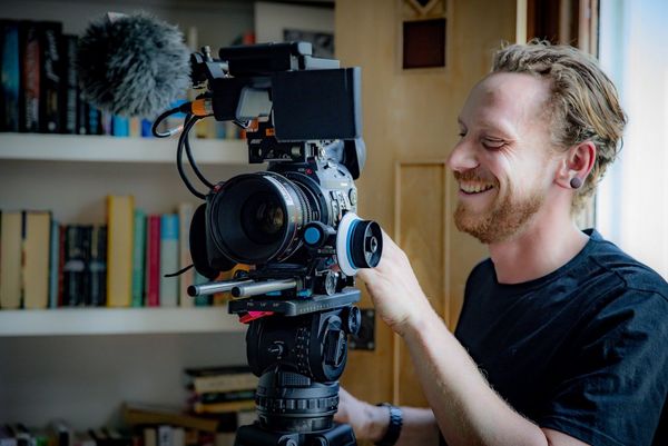 Cinematographer Steve Turvey, smiling, adjusts settings on a Canon EOS C300 Mark II camera on a tripod.