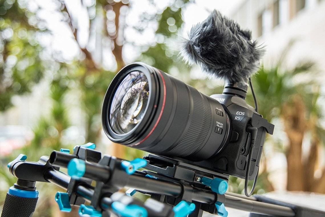 A Canon EOS R5 fitted with a microphone, attached to a filming rig.