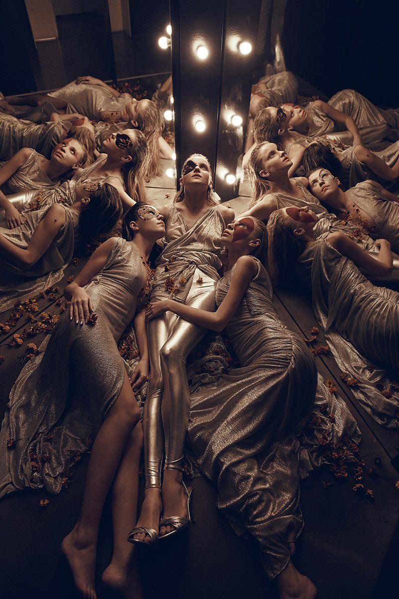 Female models wearing gold lie together in a dimly lit space with mirrors. Photo by Jaroslav Monchak on a Canon EOS 5DS R with Canon EF 24-70mm f/2.8L II USM lens.