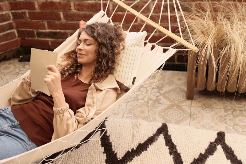 A smiling woman with long curly brown hair relaxes in a hammock.