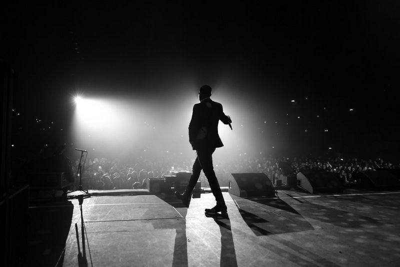 A black-and-white shot of Liam Payne silhouetted against the stage lights while performing at Wembley Arena.