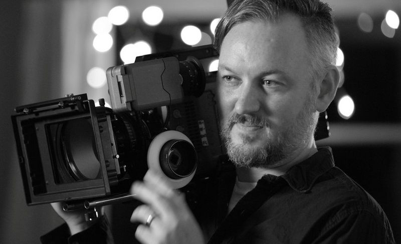 DoP Robin Fox with a camera on his right shoulder.