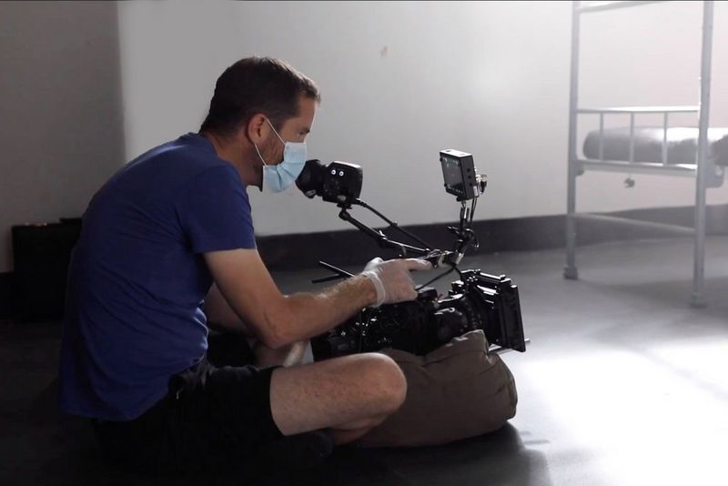 Director of photography Patrick Smith sat on the floor, wearing a protective mask, while filming in a hospital. 