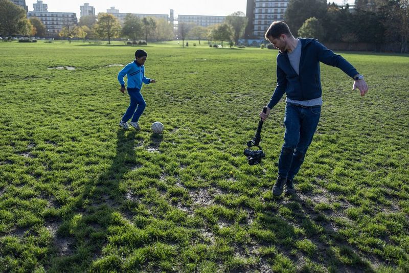 DoP Patrick Smith films a child playing football with a Canon EOS C70 cinema camera on a handheld gimbal.