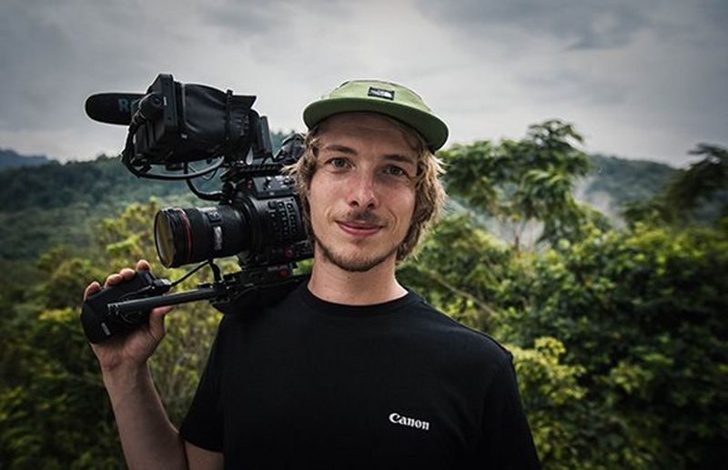 Filmmaker Michael Zomer in a forest setting with a Canon camera balanced on his shoulder.