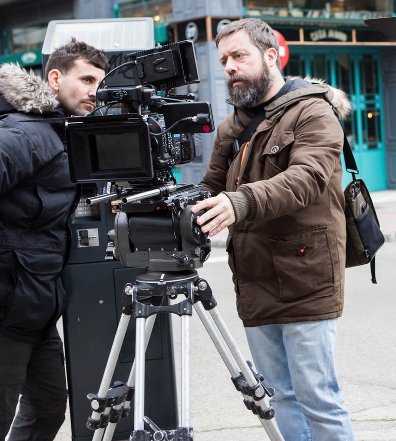 Filmmaker Juan Luis Cabellos filming with a camera mounted on a tripod.