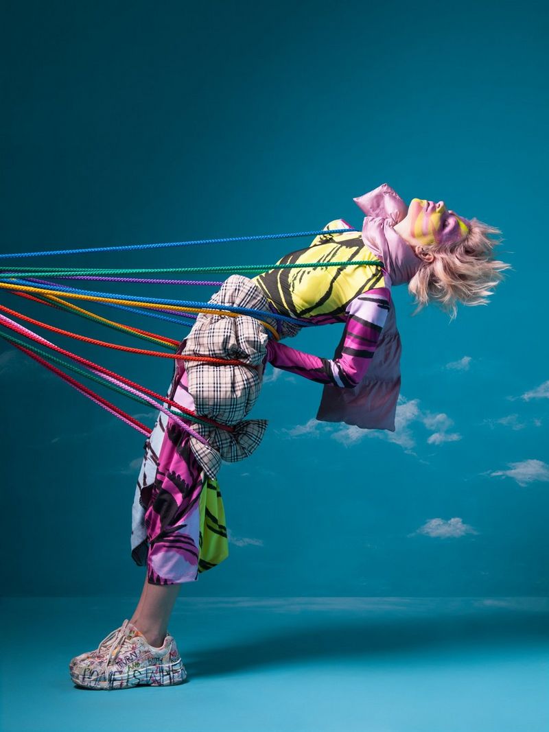 A woman leans backwards supported by colourful ribbons.