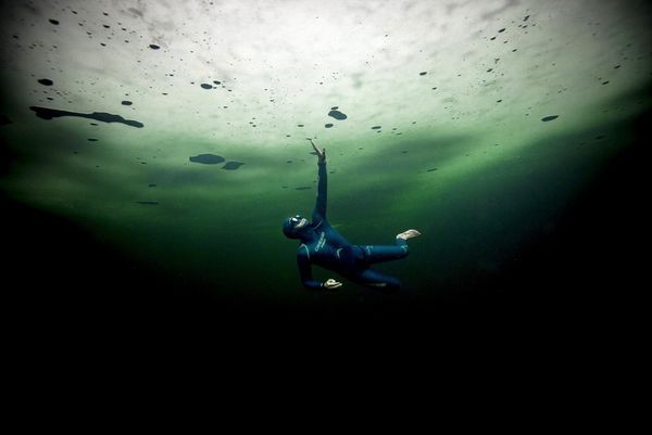 Freediver Guillaume Nry swimming under a layer of thick ice. 