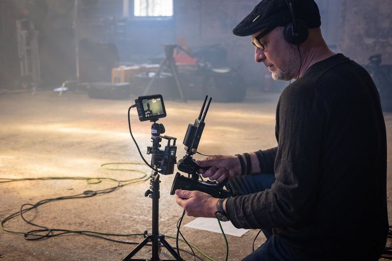 A man crouches down to film with a Canon XA45 professional camcorder.