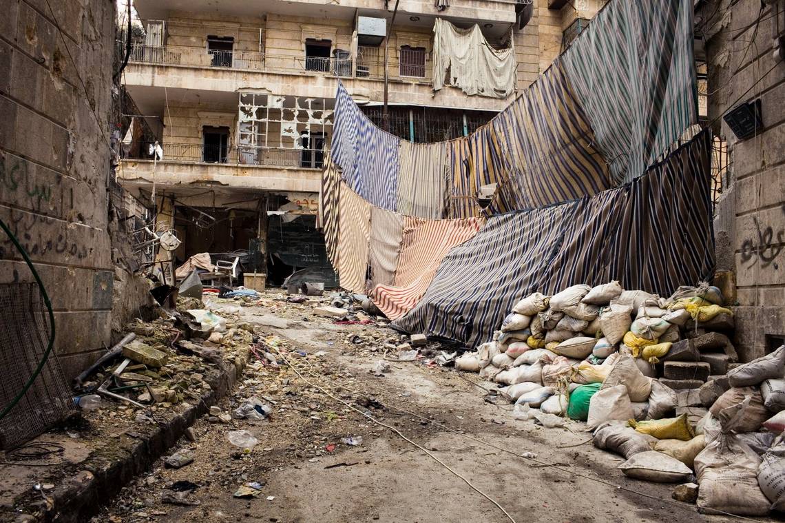 Amid the rubble of a war-torn street in southern Aleppo, sheets are strung between buildings. 