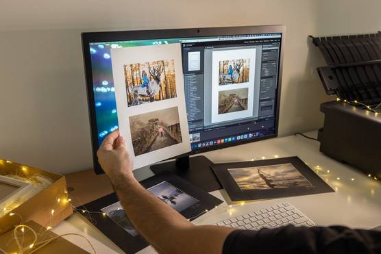  A print of two images is held up to a computer monitor showing those same two images in Canon's Professional Print & Layout software.