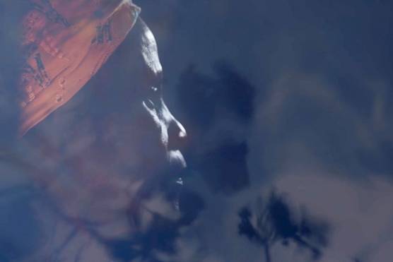 A still from a video showing a woman in side profile, her face partially obscured by shadows, shot by Laura El-Tantawy for her series Carrying Life: Motherhood and Water in Malawi.