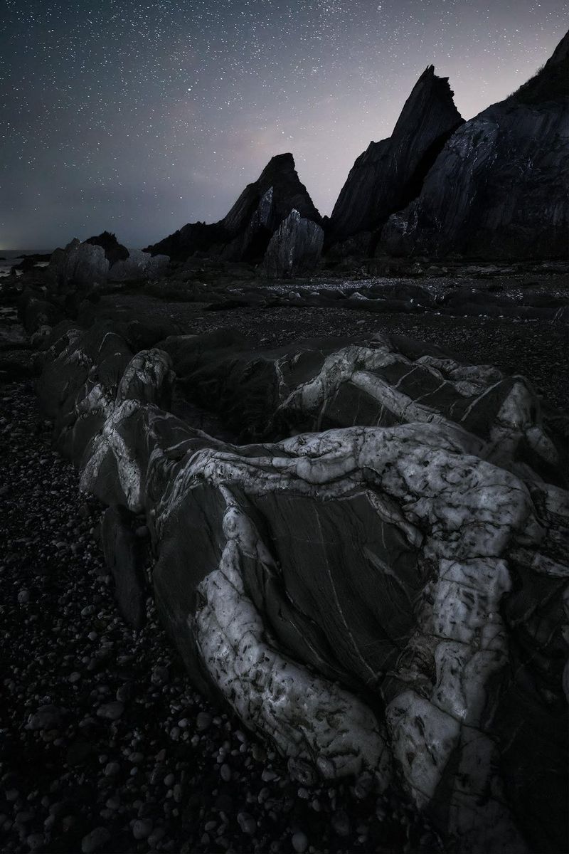 A black-and-white shot of the rocks at Westcombe Bay, Devon, England. 