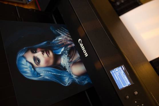 A print of a woman with blue hair emerging from a Canon imagePROGRAF PRO-1000.