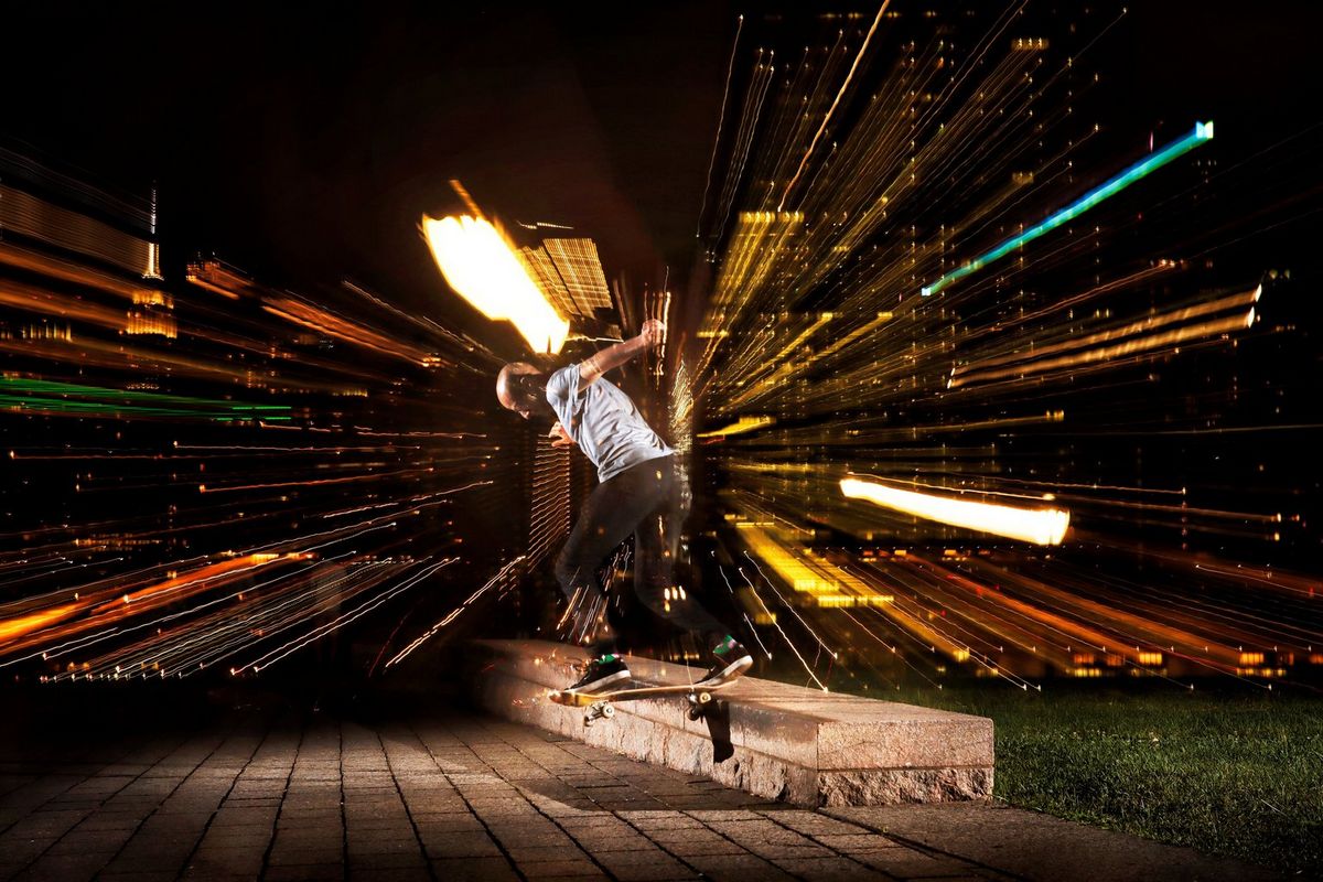A photograph of a skateboarder grinding along the edge of a low concrete block, with colourful lines of light radiating out from the centre, taken on a Canon EOS 90D camera by Josh Katz.