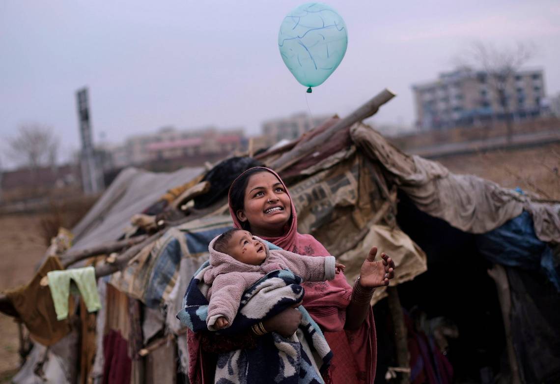 A mother and daughter play with a balloon outside their tent on the outskirts of Islamabad, Pakistan.