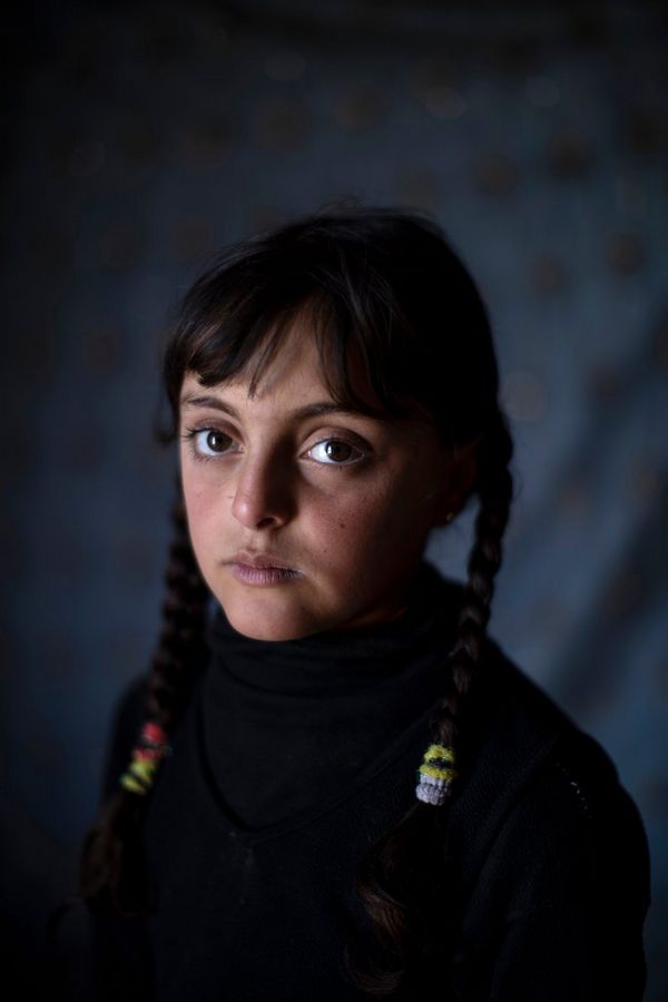 A portrait of a young refugee called Zahra, with her hair in plaits.