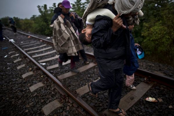 A 10-year-old Syrian refugee being carried along a railway track by her father.