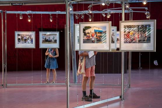 Two people look at framed photographs displayed at the Visa pour l'Image international festival of photojournalism in France.
