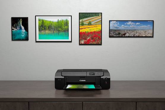 A PIXMA PRO-200 printer beneath four framed images hanging on the wall behind it.