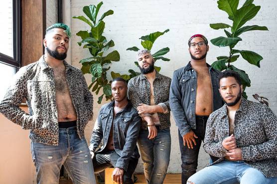A group of men pose in blue jeans and open leopard-print and denim jackets, showing their bare chests.