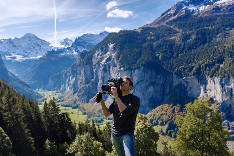 A man filming on a mountain in the Swiss Alps with a Canon Cinema EOS camera. 