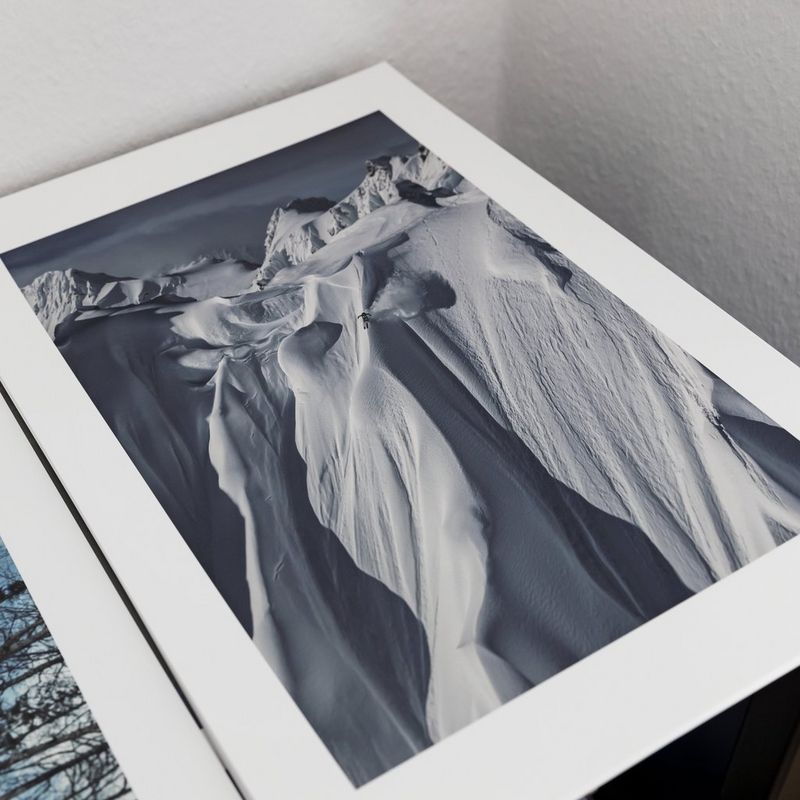 A print of a skier dwarfed by the vast, sheer mountain he is skiing down. Photo by Richard Walch.