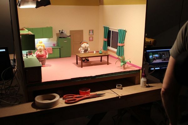 A set from No, I Don't Want to Dance! is lit, a person reviewing the photographed stop-motion footage on a screen beside the set.