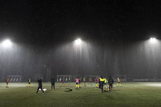 In a photo taken on a Canon 澳门现金网_申博信用网-官网3 by Eddie Keogh, football players practise under the floodlights on a dark and rainy night.
