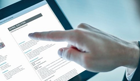 Close up of a right hand pointing at small text on a tablet screen with the index finger.