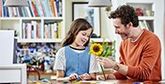 A father and daughter making papercraft flowers.