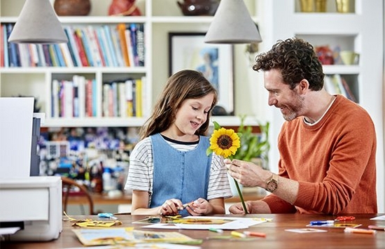 A father and daughter making papercraft flowers.