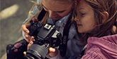 A mother and daughter look at the back of a Canon EOS 250D.