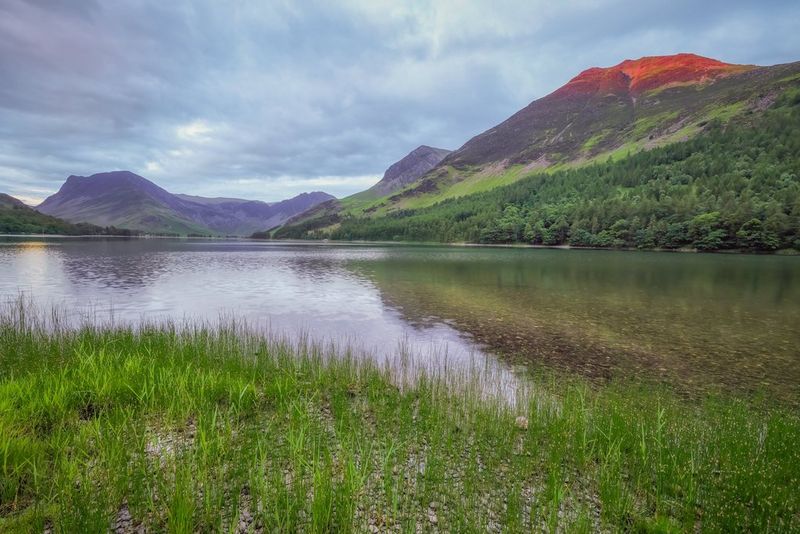 Un lac entouré de montagnes sous un ciel parsemé de nuages.