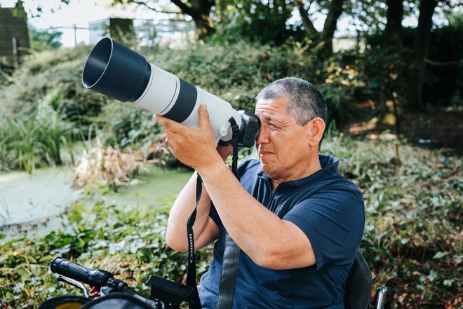 Peter Lau ţine la ochi un aparat foto Canon cu un obiectiv Canon RF 200-800mm F6.3-9 IS USM ataşat.