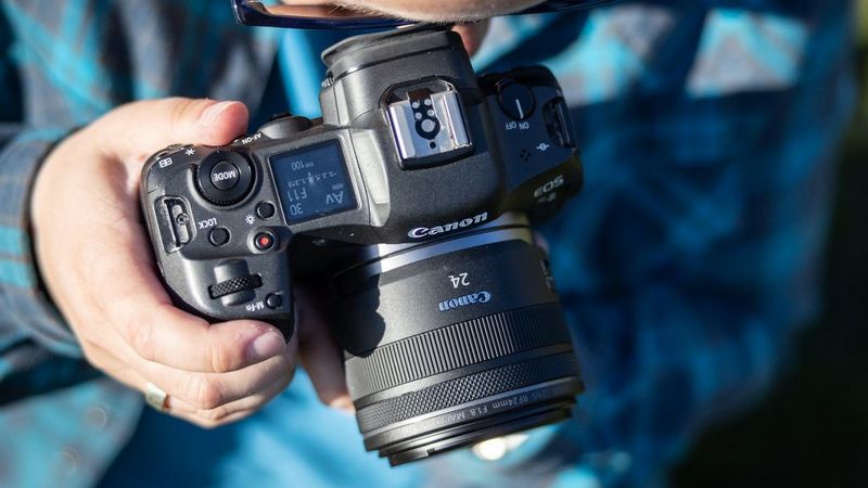Person holding a Canon camera with a wide-angle lens.