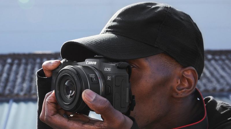 Person holding a Canon camera with a prime lens.