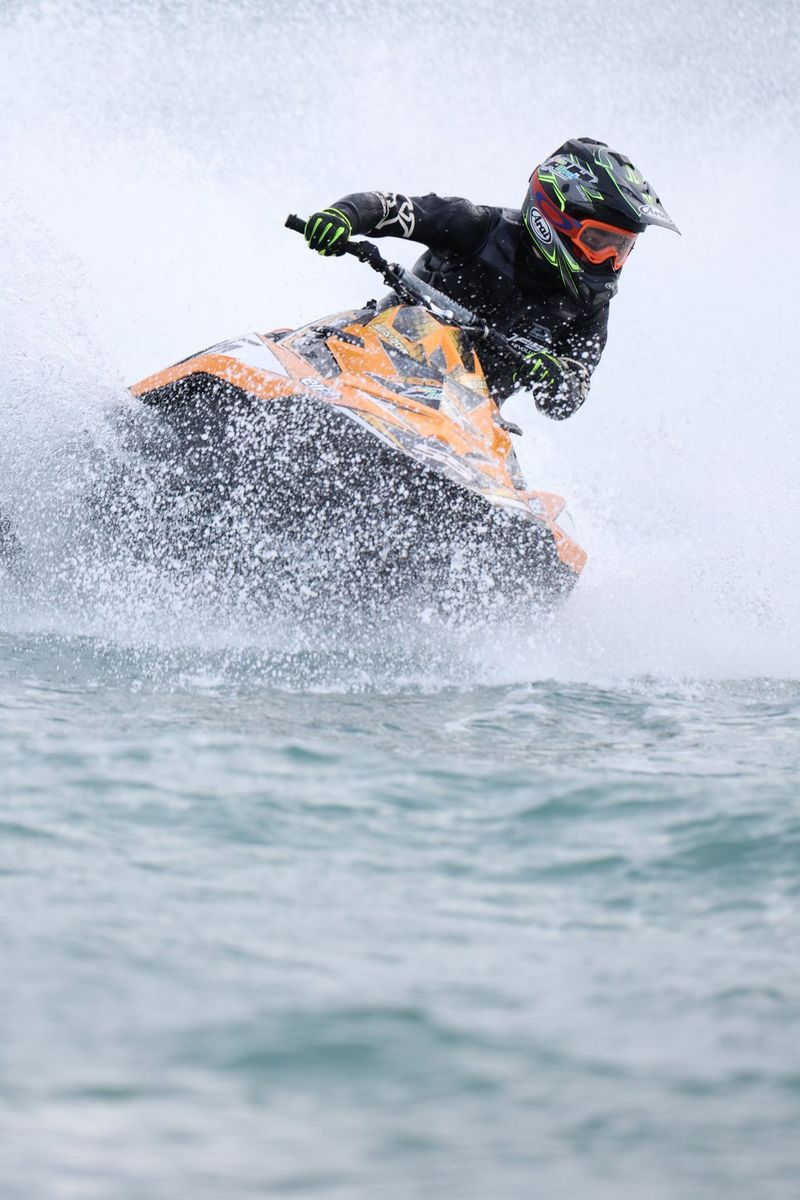 A jet skier corners at high speed throwing up a cloud of water spray.
