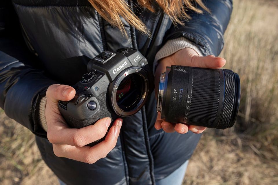 Bir Canon EOS R fotoğraf makinesi ve Canon RF 24-105mm F4-7.1 IS STM lens tutan eller.