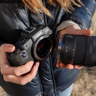 ידיים מחזיקות מצלמת Canon EOS R ועדשת Canon RF 24-105mm F4-7.1 IS STM.