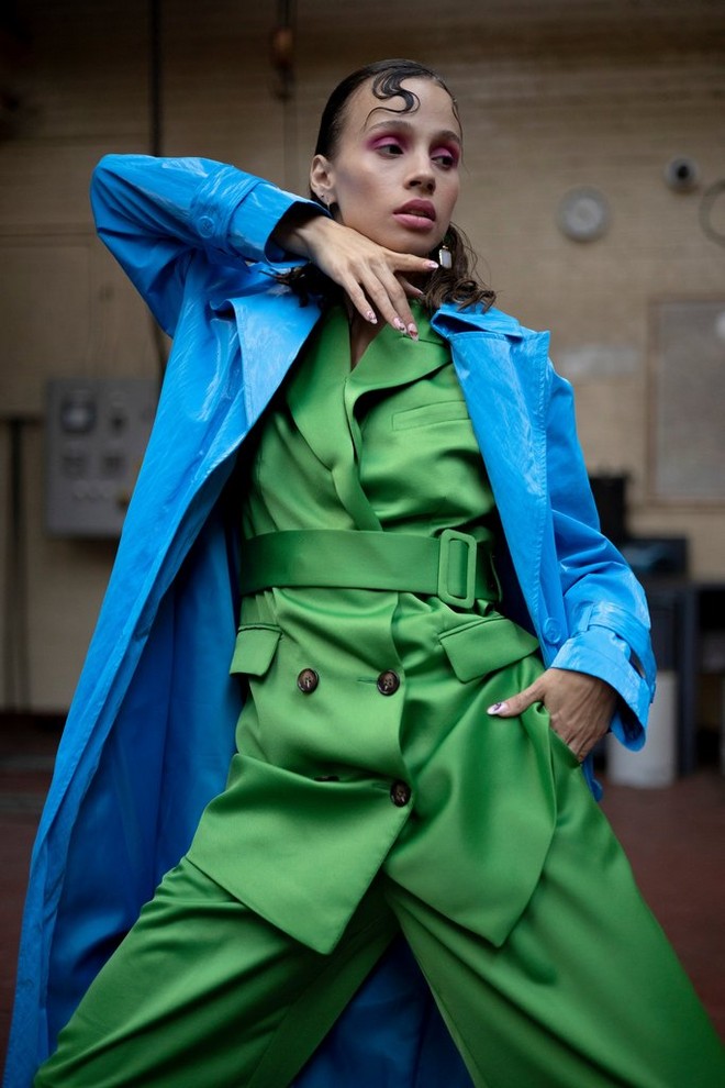 A portrait of a woman wearing a green suit and a blue coat.